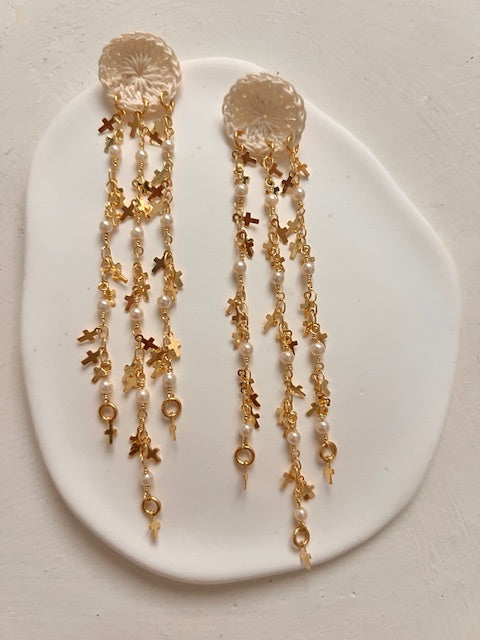 Pendientes alargadas en crochet con caídas de cadenas en oro laminado, perlas de cristal y múltiples cruces.